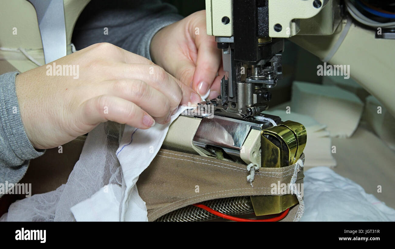 Close up portrait of hands of seamstress sewing using industrial sewing machine. Stocking manufacturing in a factory. Stock Photo