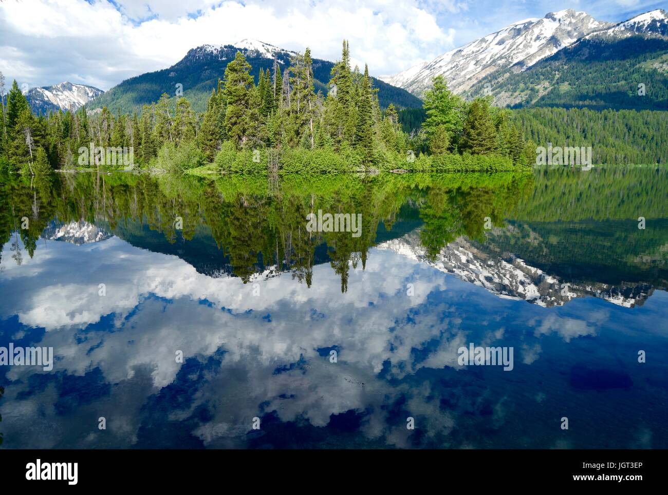 Mountains and trees reflected in a clear lake Stock Photo - Alamy