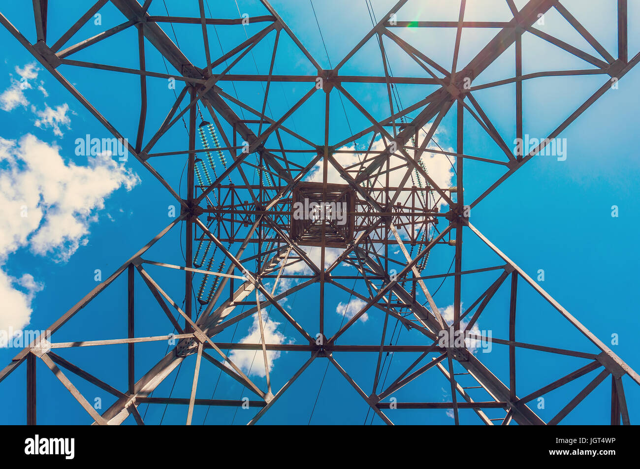 Tower electro gear consisting of a solid metal on a background of blue sky with white clouds. Bottom view Stock Photo