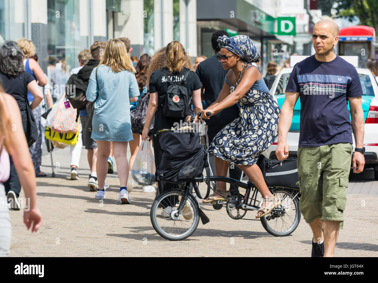 Black woman riding a collapsible bicycle on the pavement. Stock Photo