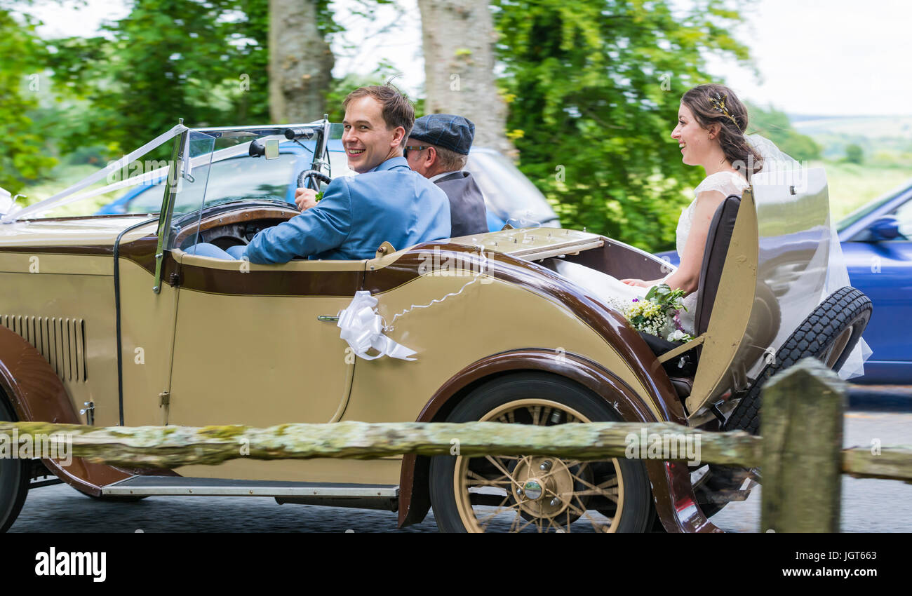 Bride and Groom travelling in an old car on their wedding day. Happy couple. Getting married in the UK. Newly weds. Just married. Stock Photo
