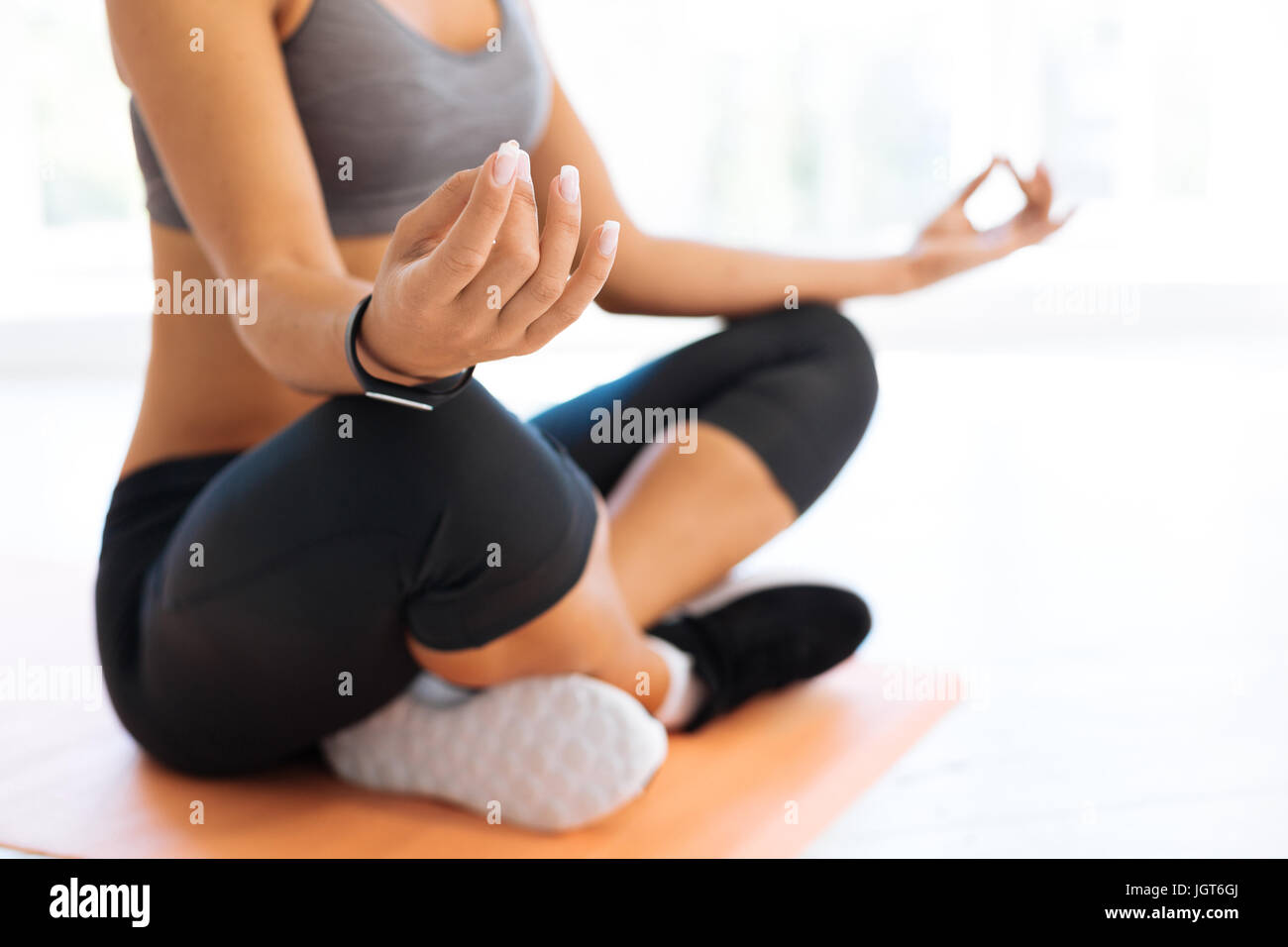 Healthy woman sitting on the floor while meditating Stock Photo