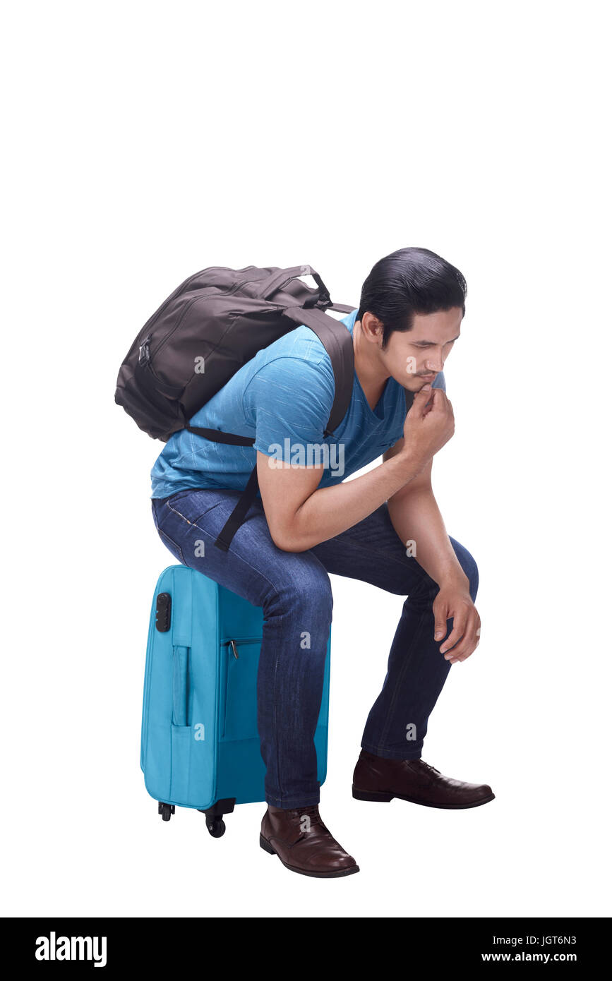 Portrait of asian tourist sitting on suitcase thinking isolated over white background Stock Photo
