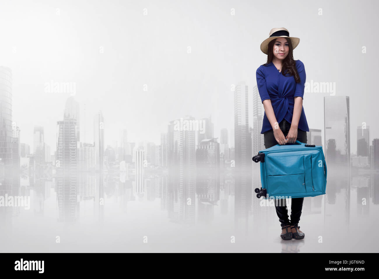 Pretty asian traveler woman carrying blue suitcase over futuristic background Stock Photo