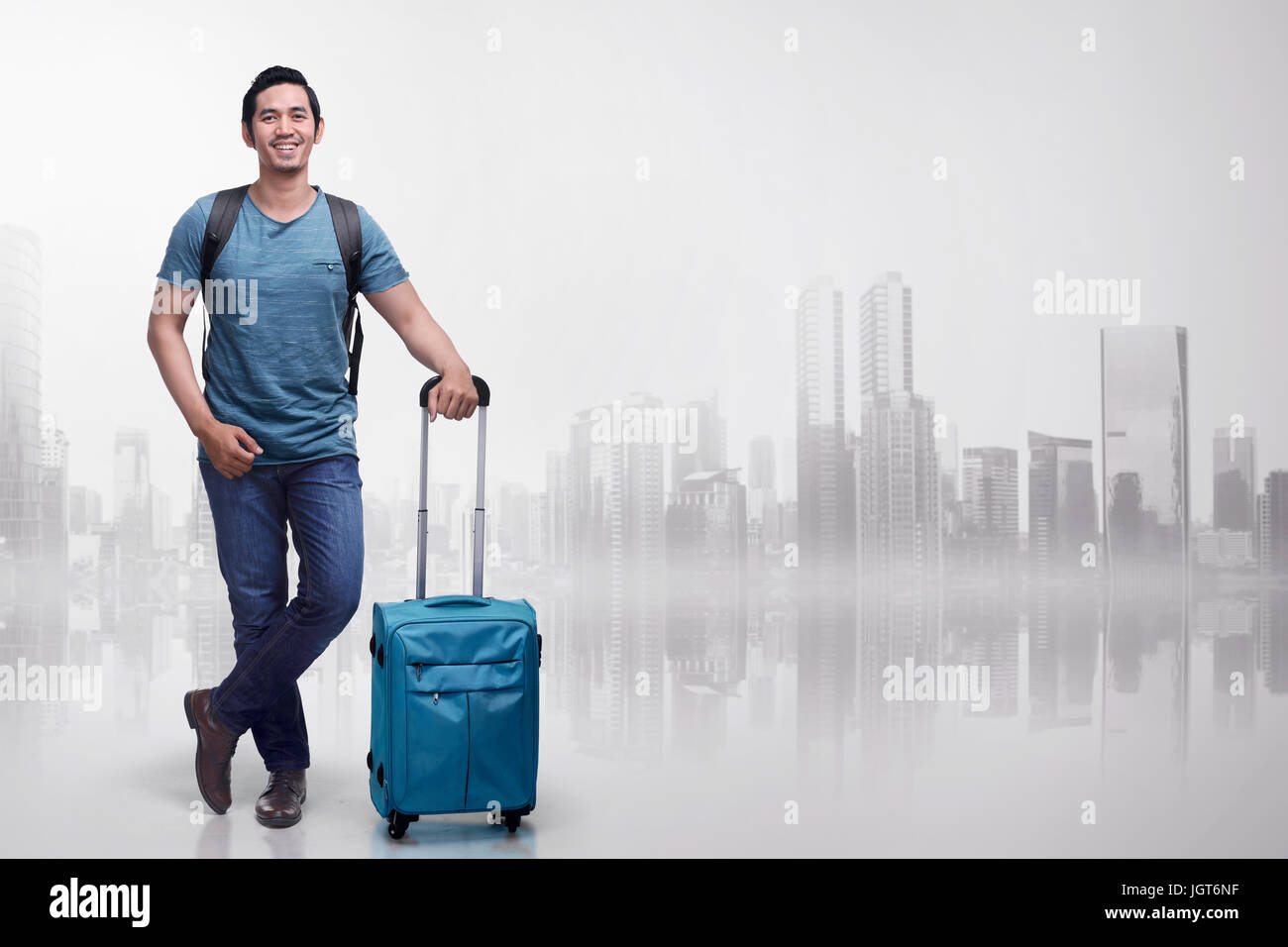Young asian tourist man with suitcases standing over futuristic background Stock Photo