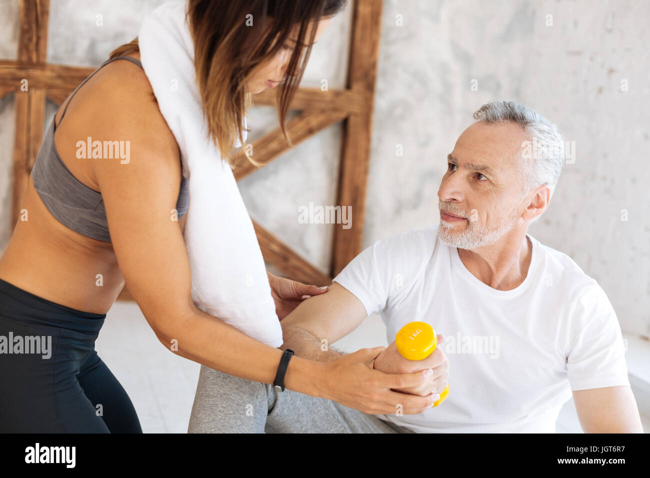 Attentive brunette helping to raise arm correctly Stock Photo