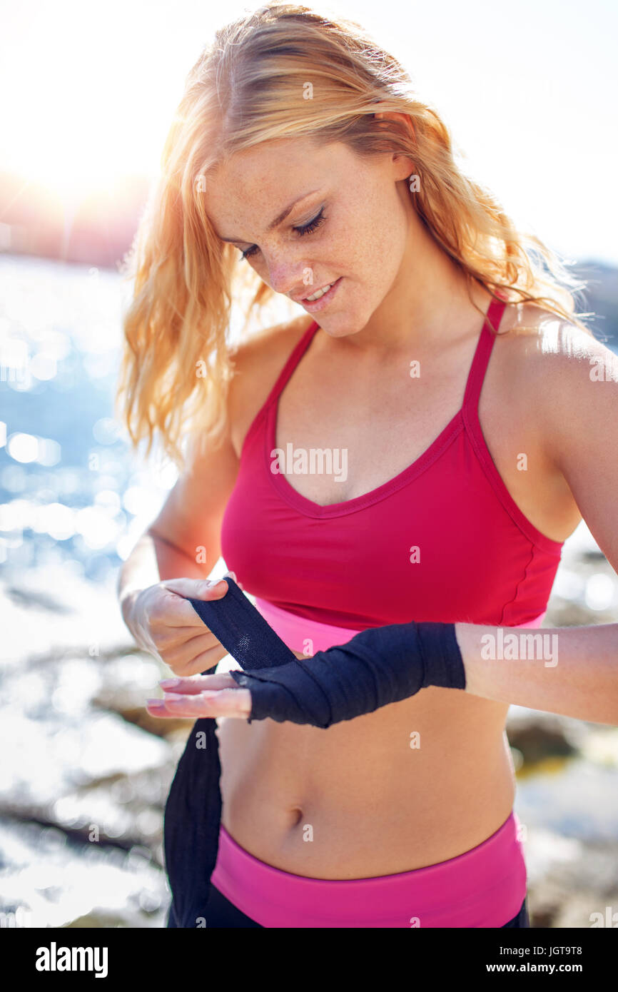 Young boxer woman wrapping hands at sea before workout Stock Photo