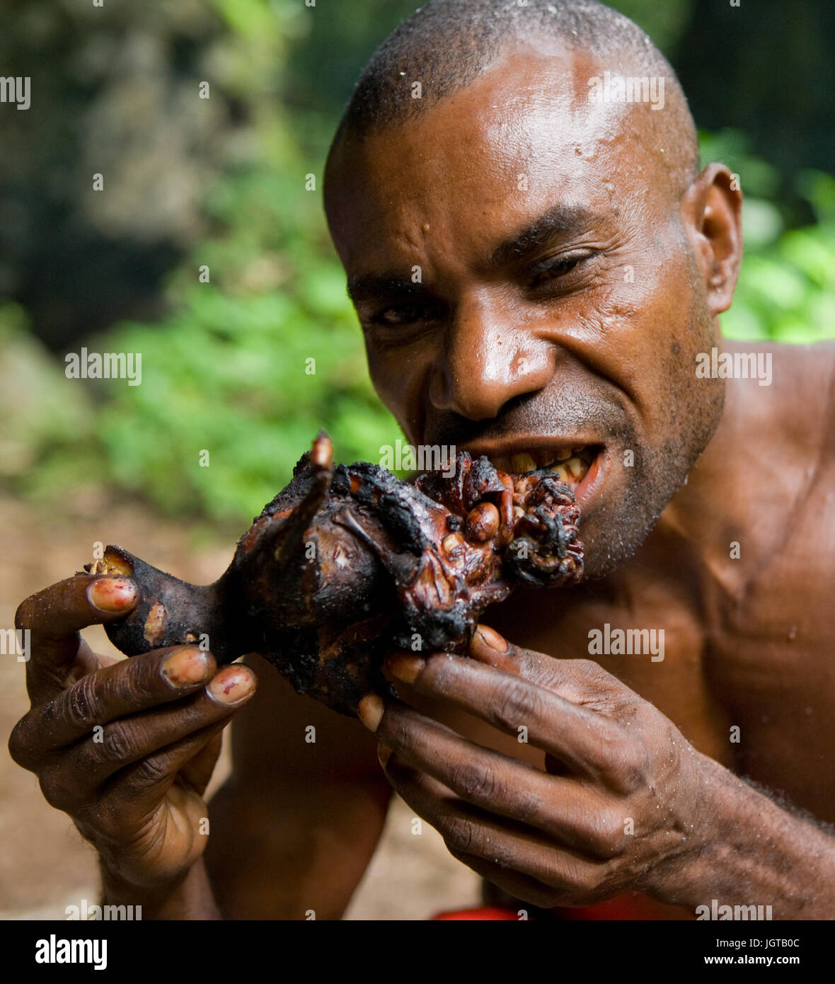 NEW GUINEA, INDONESIA - 13 JANUARY: Man tribe Yaffi eating a piece of meat. Stock Photo