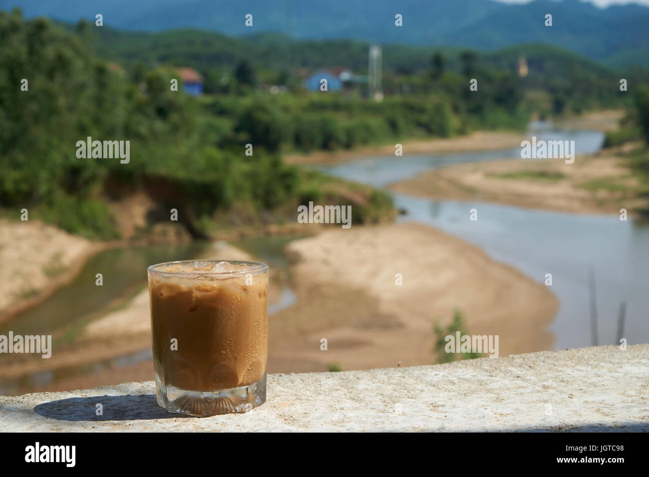 Iced coffee or caffe latte in front of a nice blurred landscape in Vietnam, Phong NhaKe Bang Nationalpark. Stock Photo