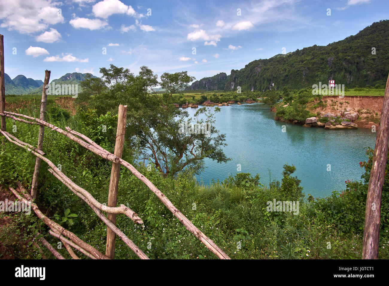 Wooden fence with a turquoise colored river near the town of Phong Nha in the National Park of Phong Nha Ke Bang, Vietnam. Stock Photo