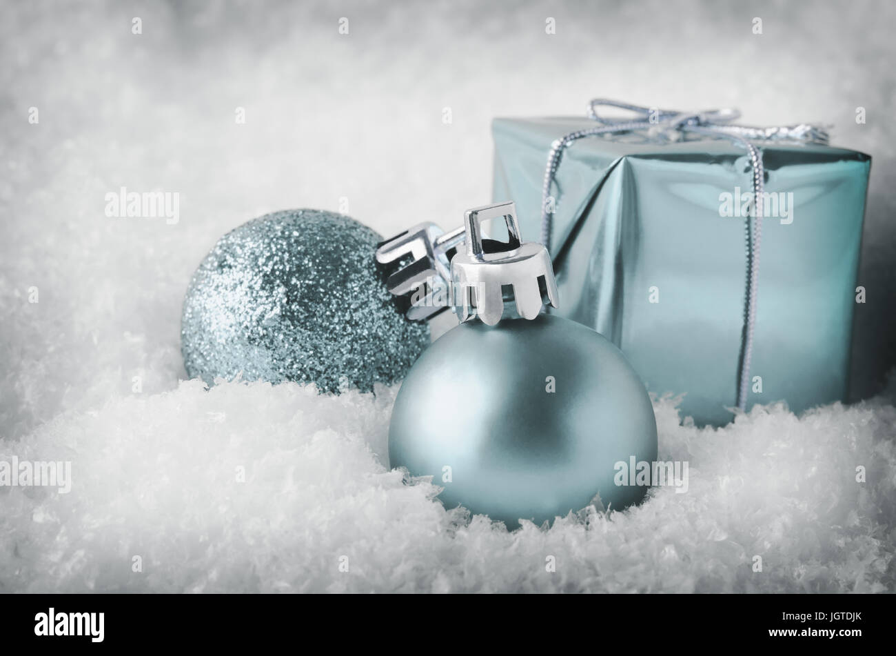 An arrangement of pale blue Christmas decorations sinking into soft, white artificial snow.  Includes glitter and matte  baubles and gift box.Cool, pa Stock Photo