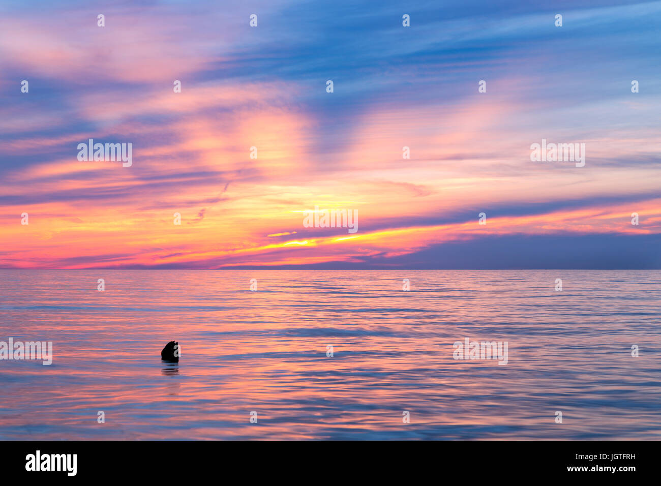 Lake Michigan Sunset - Sun beams raise up from the horizon and vivid colors reflect on the surface of Lake Michigan during sunset Stock Photo