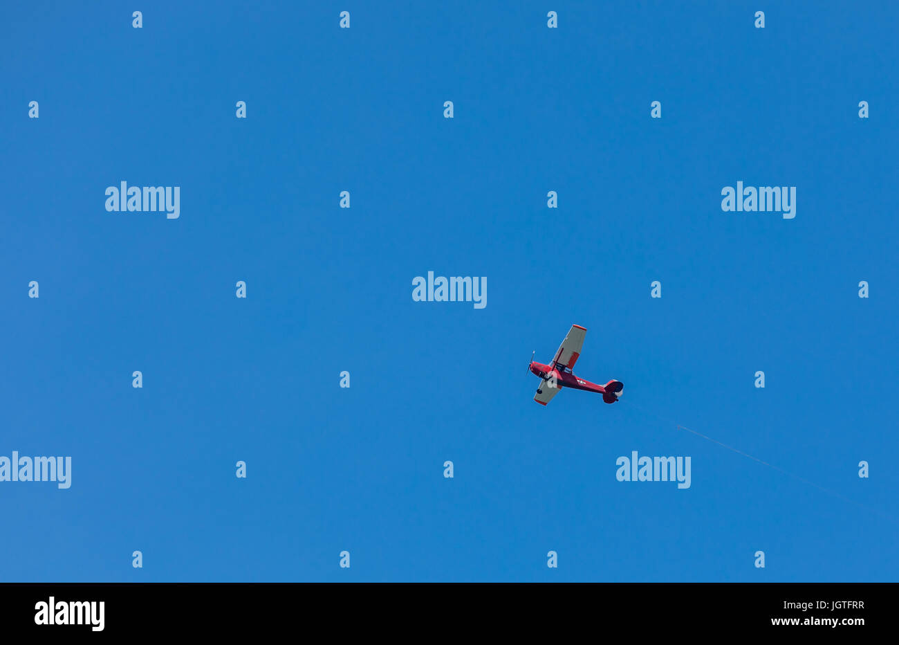 a bright red single engine plane flying over Sag Harbor, NY Stock Photo
