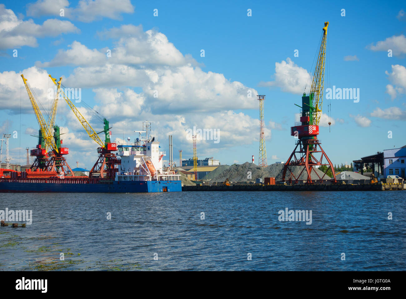 Freight cranes operate at sea vessel unloading in the port. Stock Photo