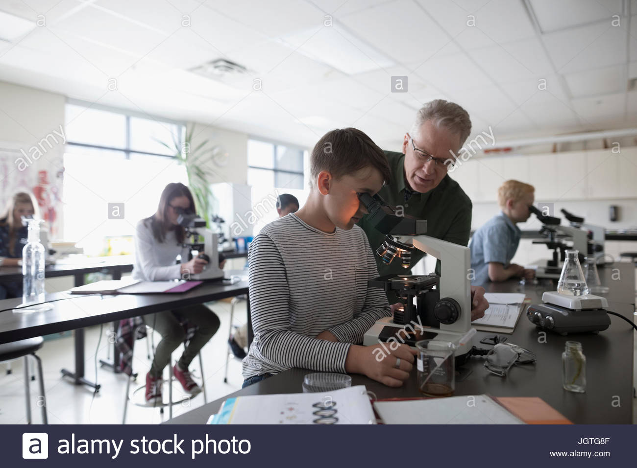 Teacher and middle school student using microscope, conducting