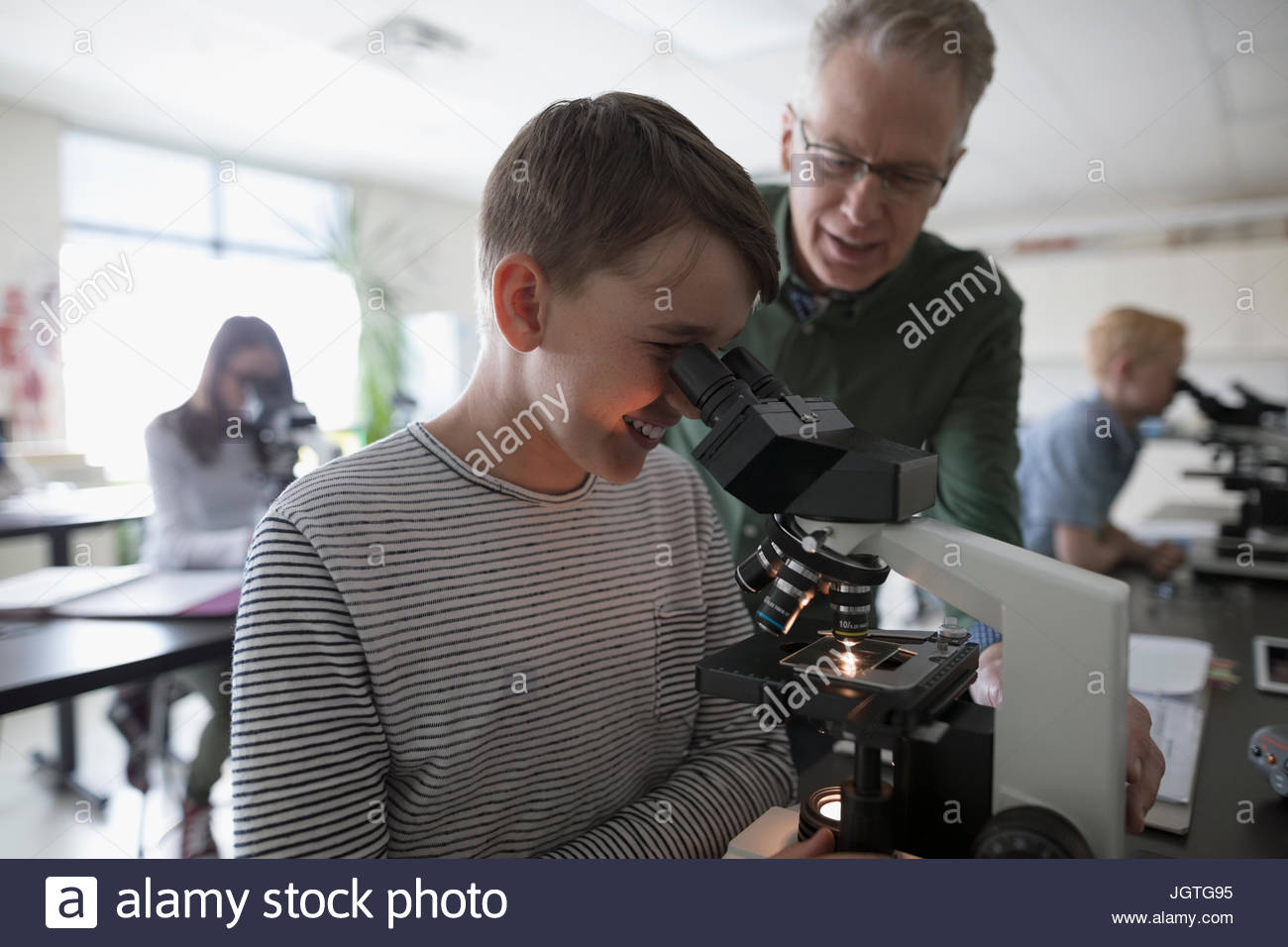 Teacher and middle school student using microscope, conducting
