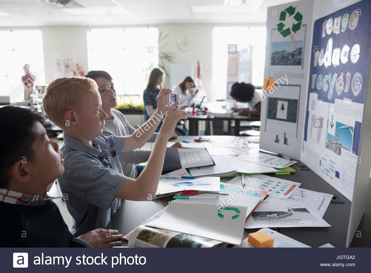 boy middle school student photographing science project poster with