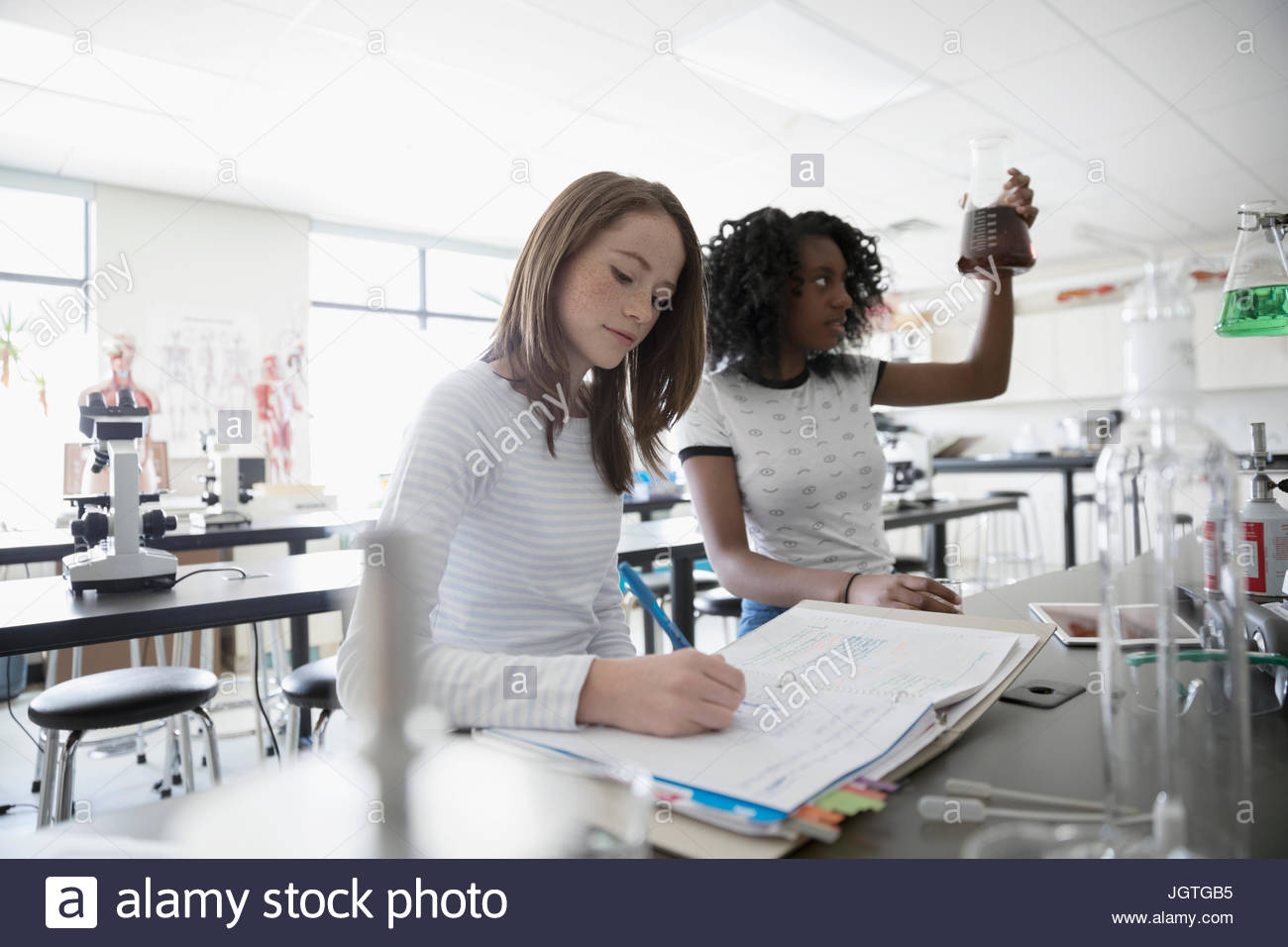 Girl middle school students conducting scientific experiment in science