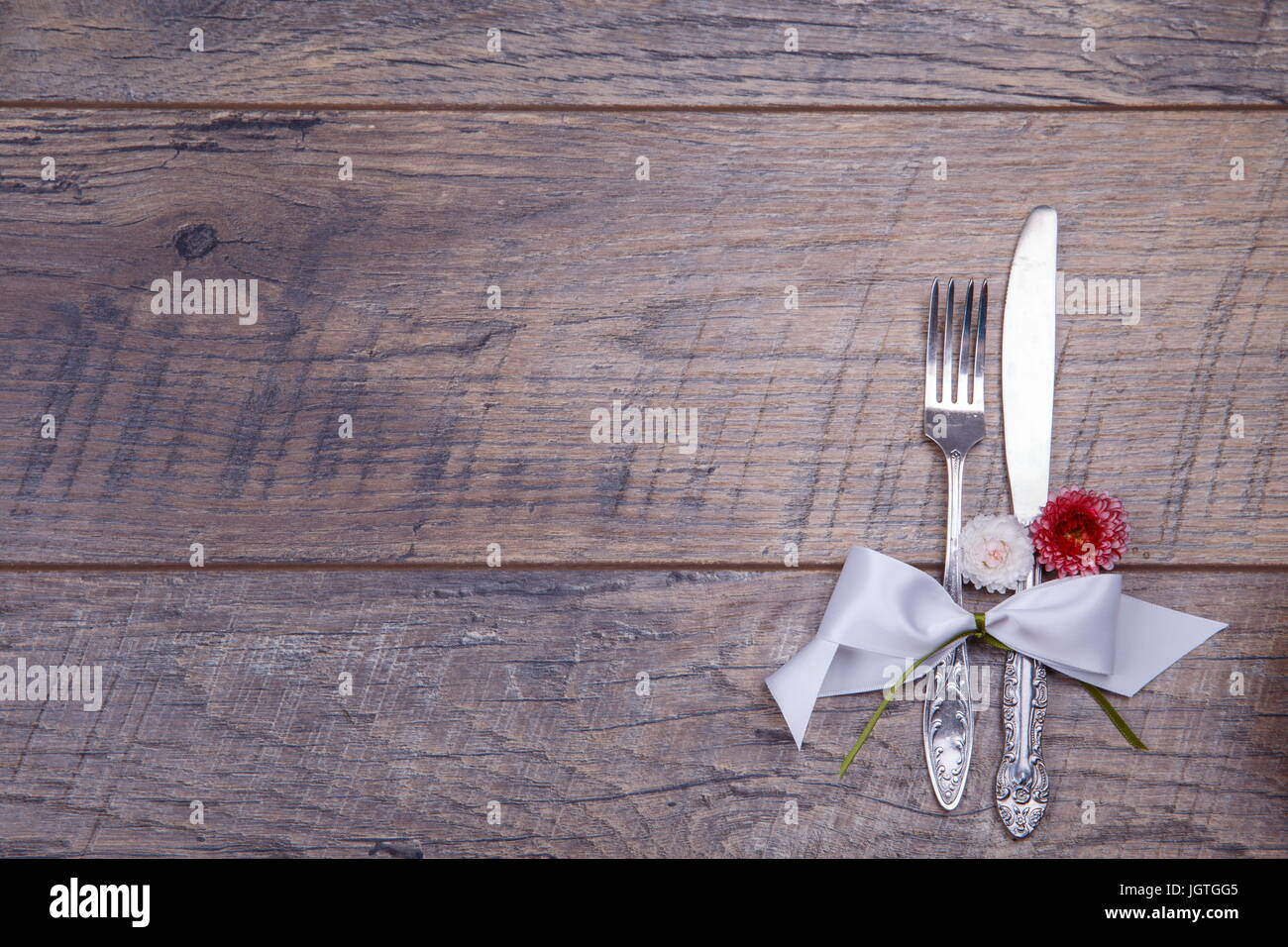 Place table settings with fork and knife, tied with a white satin