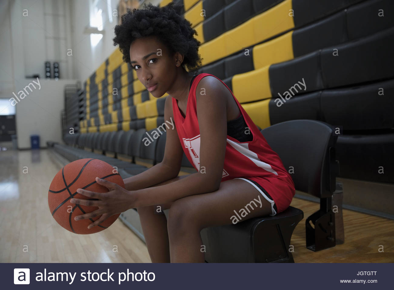 Portrait confident female college basketball player in gymnasium Stock Photo
