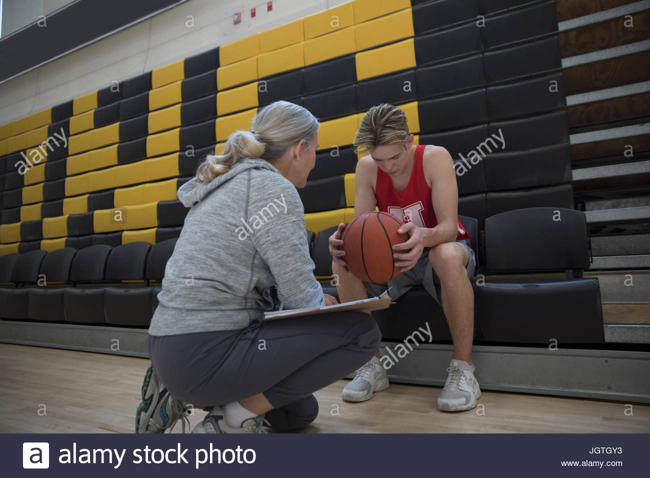 Female coach coaching male college basketball player in gymnasium Stock Photo
