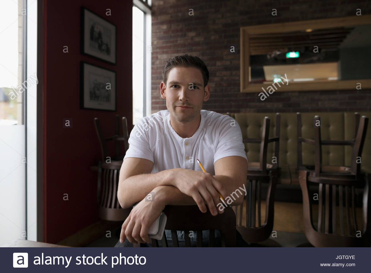 Portrait confident waiter straddling chair in diner Stock Photo