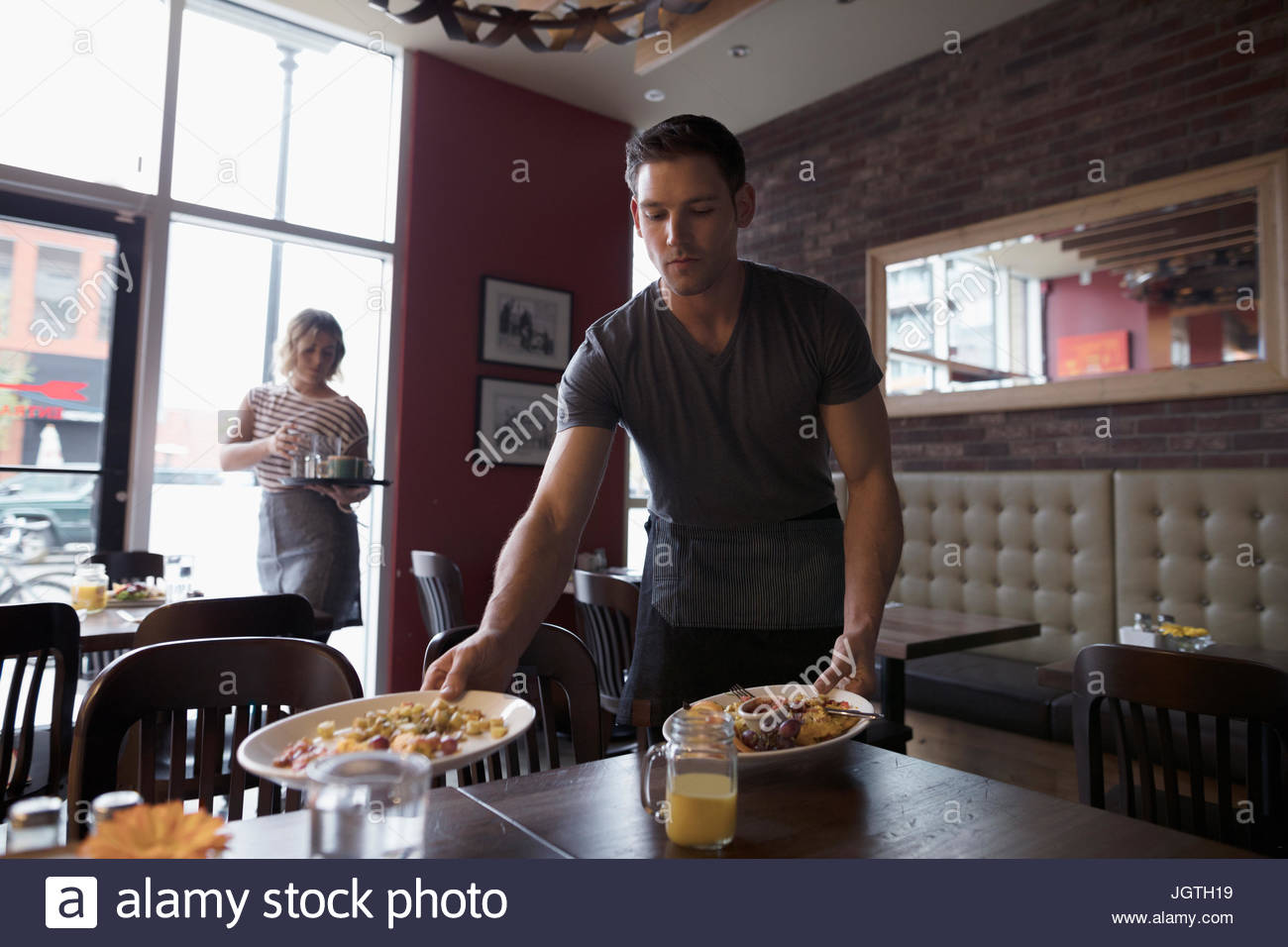 Waiter bussing table in diner Stock Photo