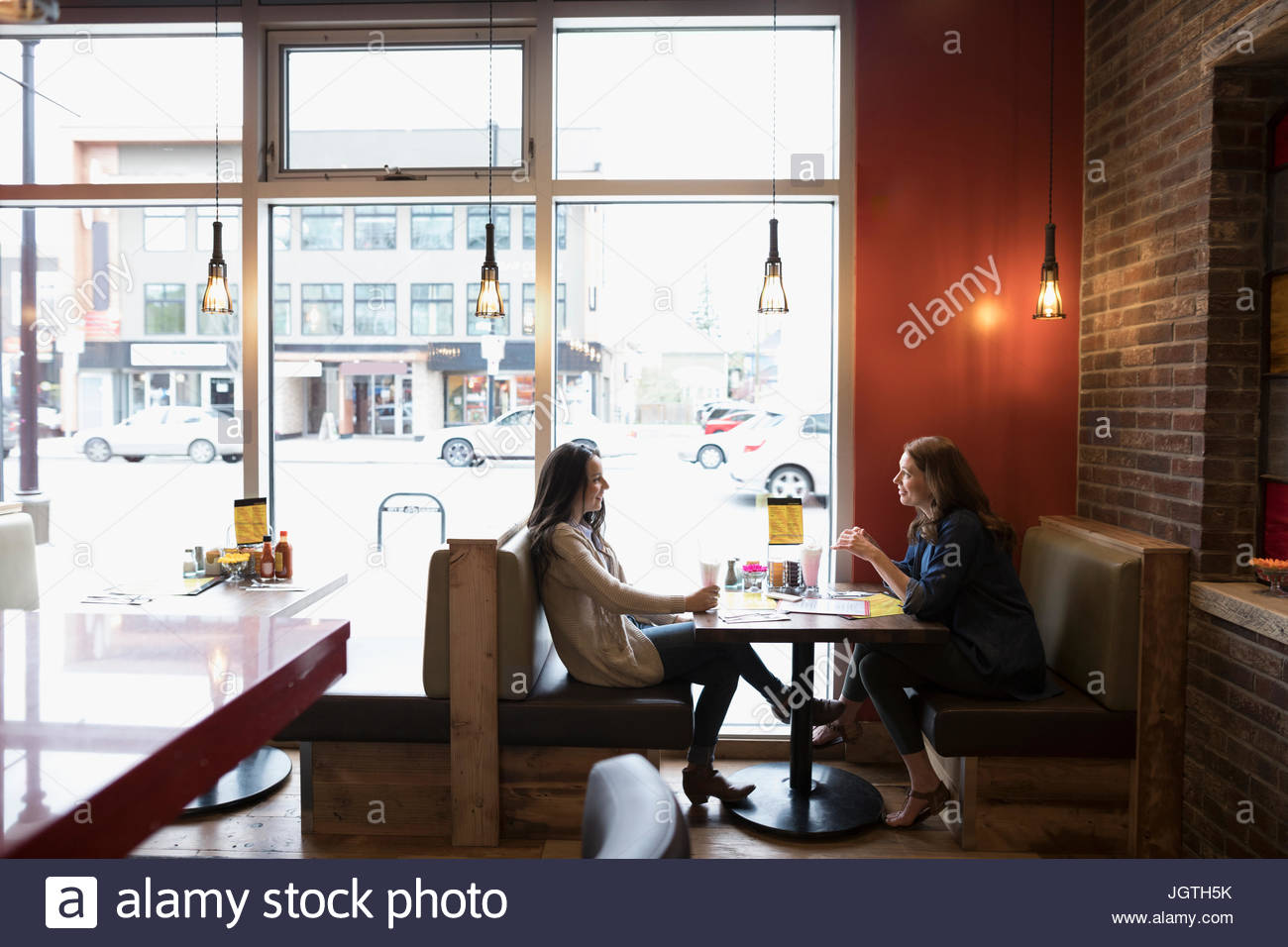 Mother and teenage daughter talking, dining at diner booth Stock Photo