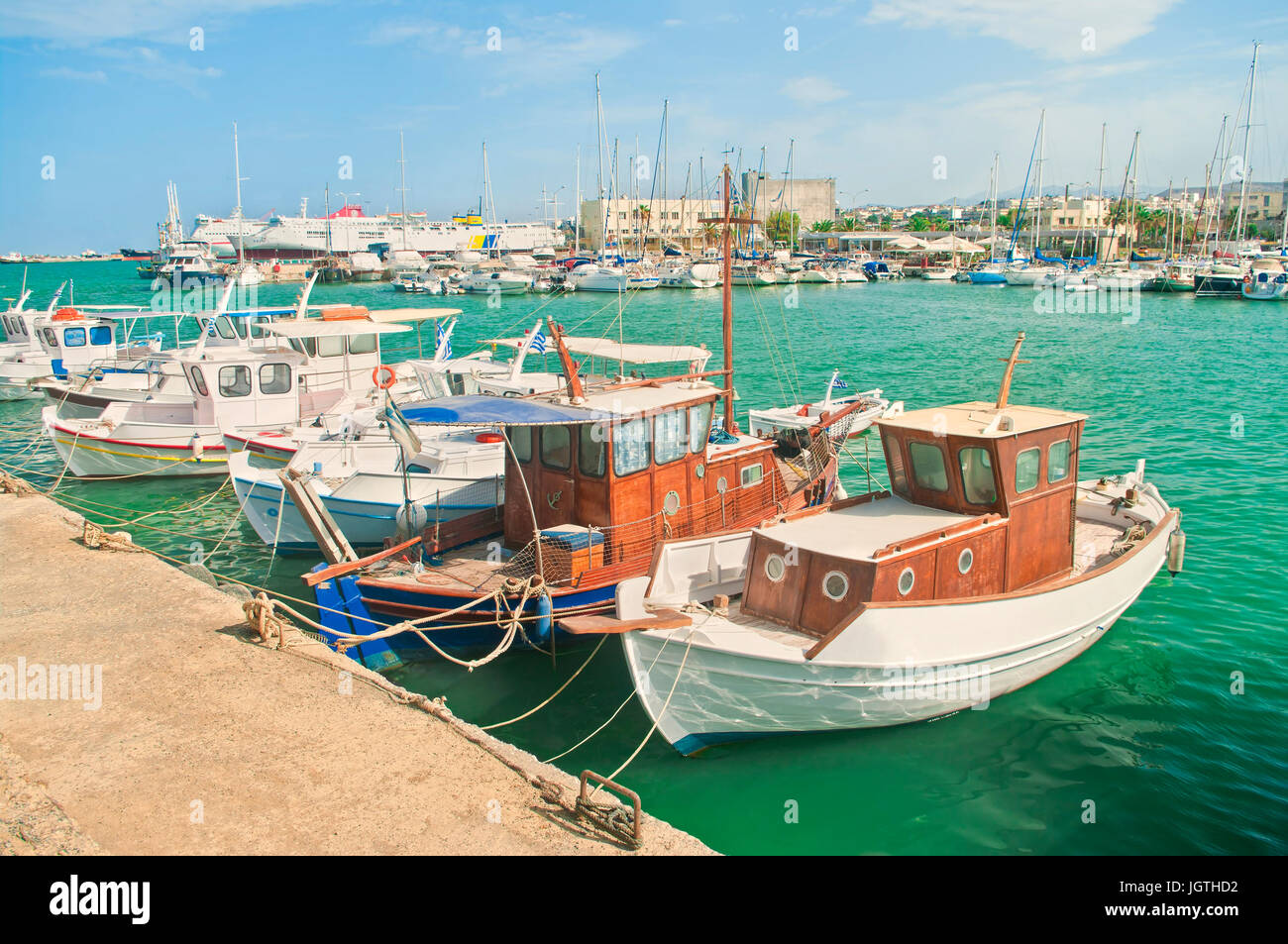 beautiful small white wooden fishing boats moored at port on sunny summer day in Iraklio, Crete, Greece Stock Photo