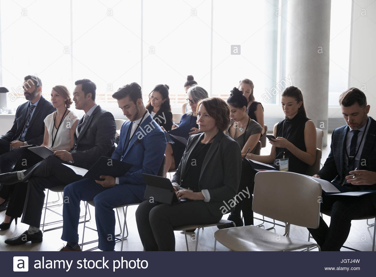 Business people with paperwork using cell phones and digital tablets in conference audience Stock Photo
