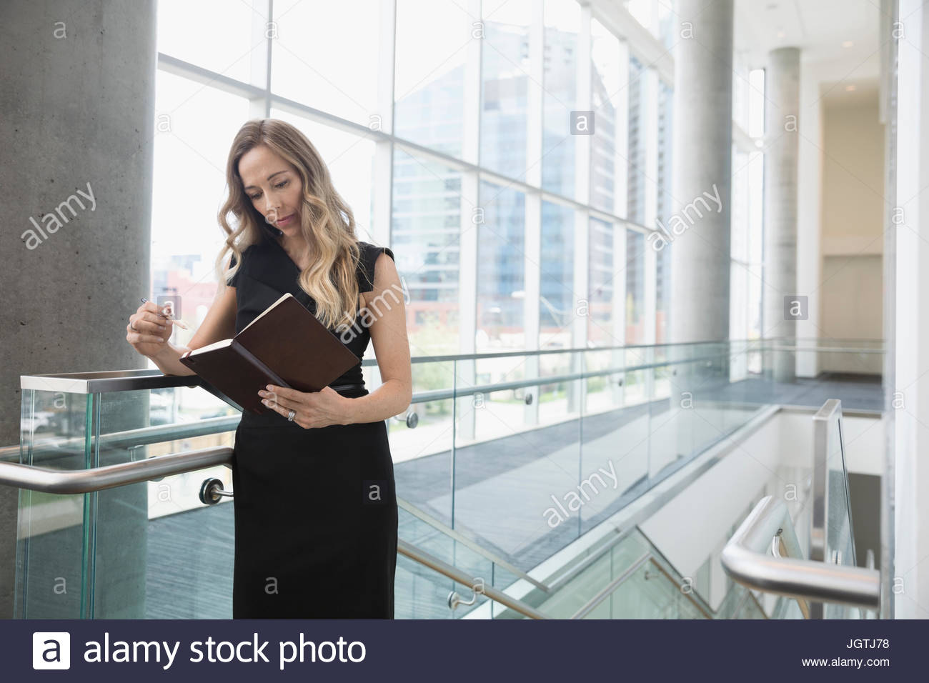 Businesswoman viewing journal schedule at top of office stairs Stock Photo