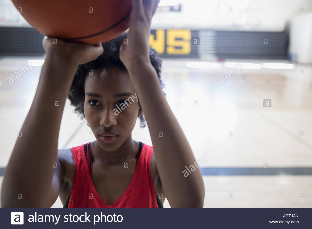 Focused female college basketball player shooting free throw in gymnasium Stock Photo