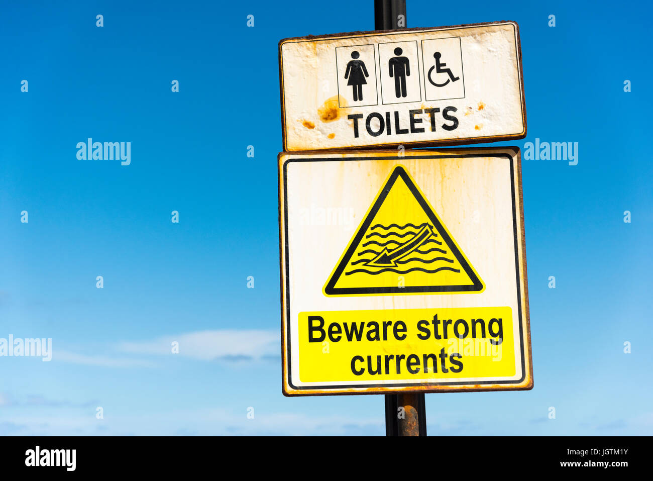 A sign warning of strong currents and dorections for toilets at St Julians Malta Stock Photo
