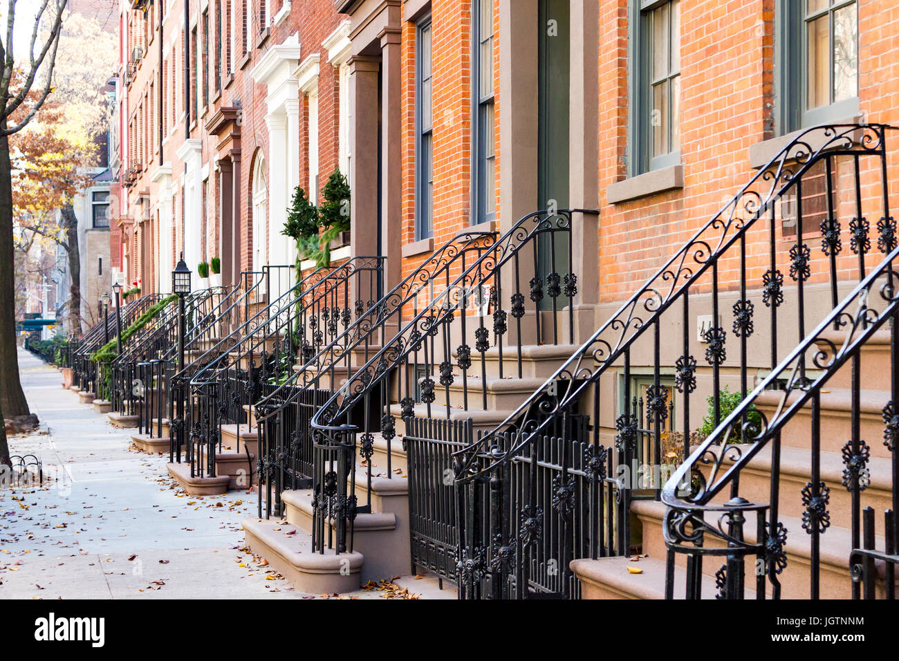 Row of old historic brownstone buildings along an empty sidewalk block in the Greenwich Village neighborhood of Manhattan, New York City NYC Stock Photo