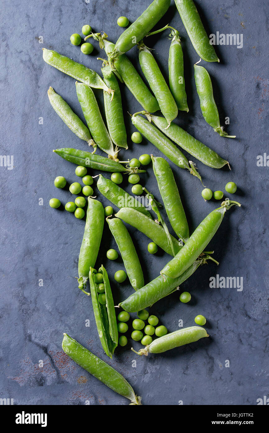 Young organic green pea pods and peas over blue gray texture metal background. Top view with