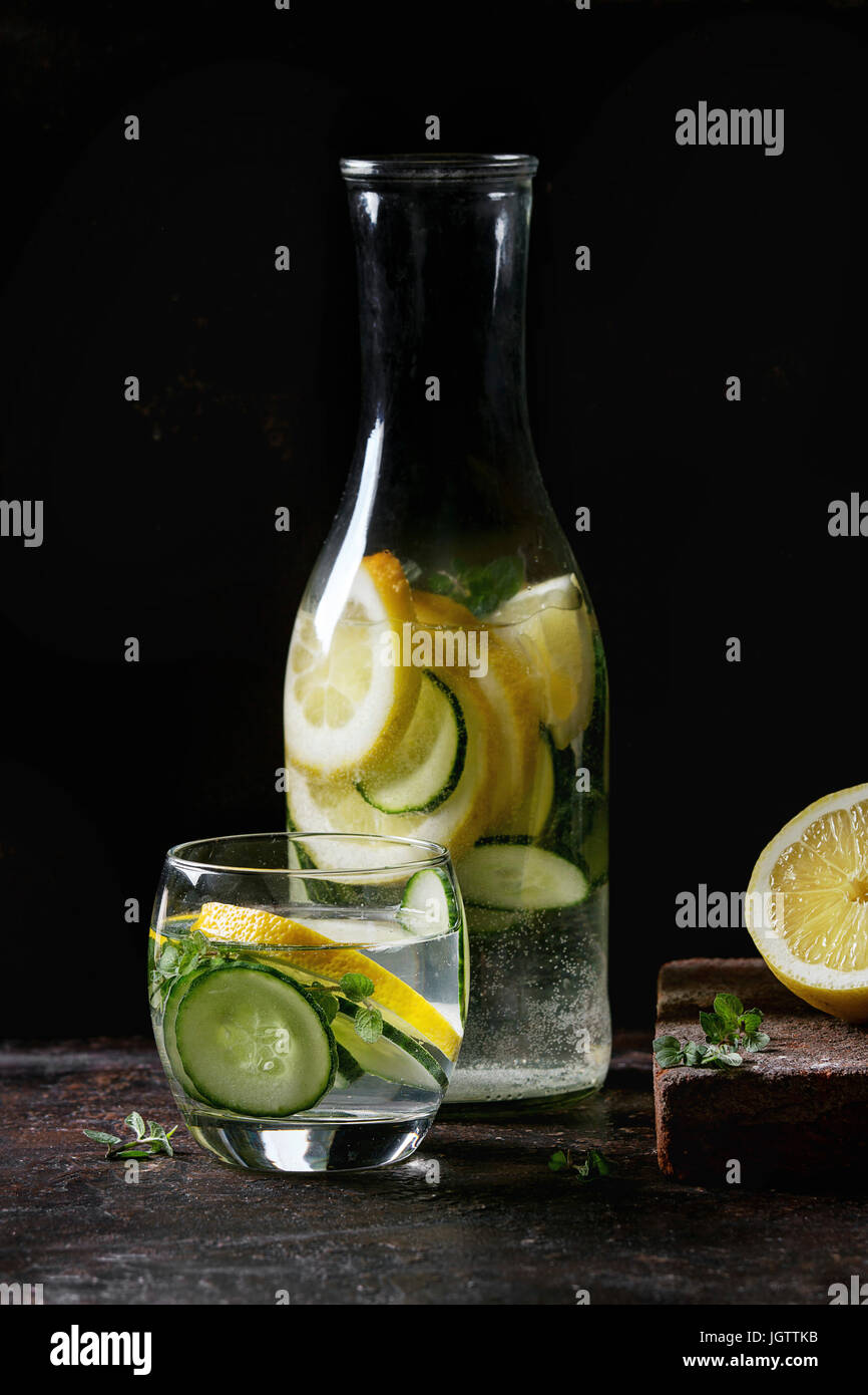 Citrus cucumber sassy sassi water for detox in glass bottle on dark black background. Clean eating, healthy lifestyle concept, sunlight Stock Photo