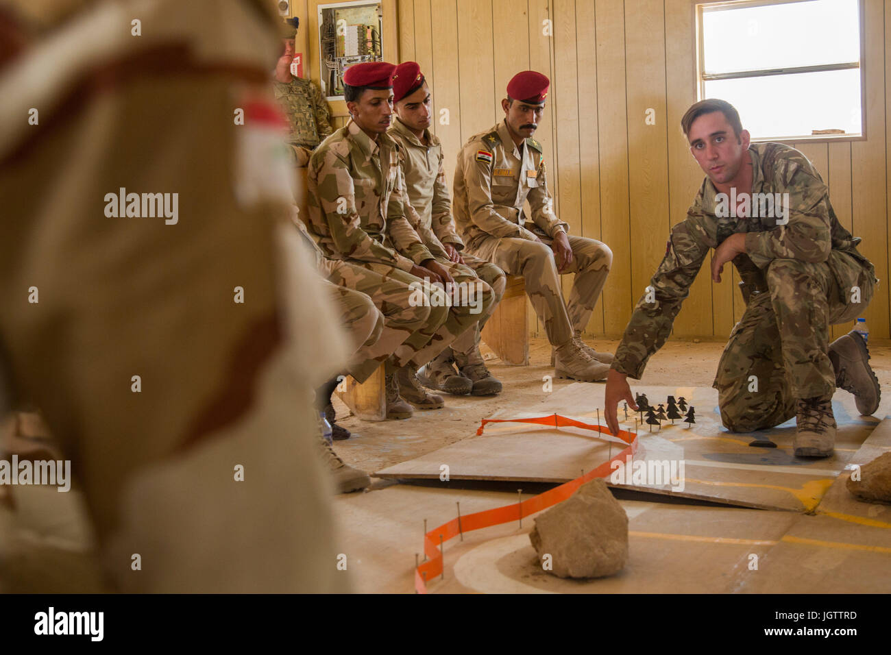 British trainer Lance Cpl. Andrew shows Iraqi soldiers where to suspect improvised explosive devices on a map during a counter I.E.D. class at Camp Al Asad, Iraq, July 2, 2017. This training is critical to enabling local security forces to liberate their homeland from ISIS. CJTF-OIR is the global Coalition to defeat ISIS in Iraq and Syria.  (U.S. Army photo by Spc. Cole Erickson) Stock Photo