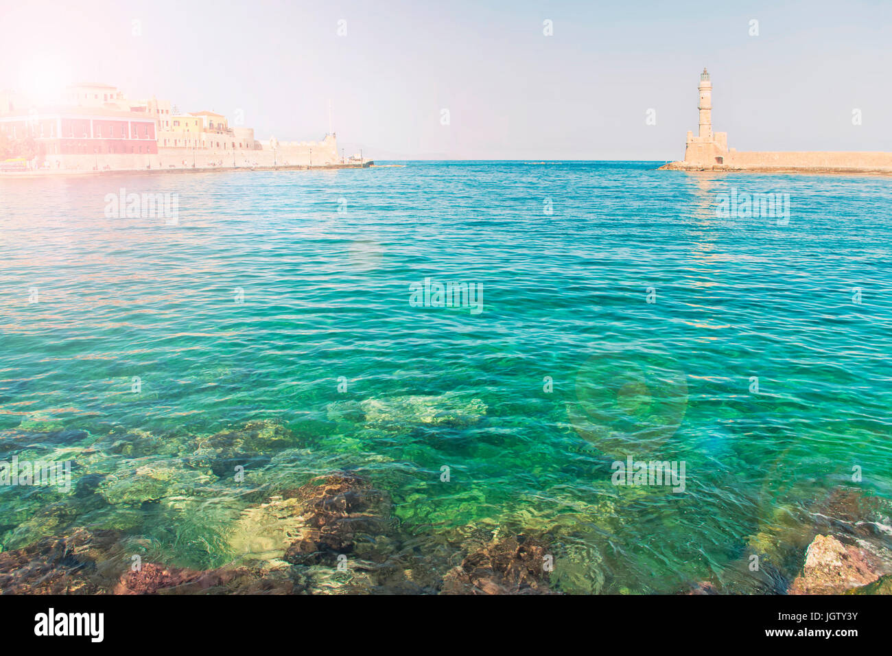 cross-processed shot of clear waters of Mediterranean sea in morning in old part of Chania with sun shining behind buildings, Crete Stock Photo