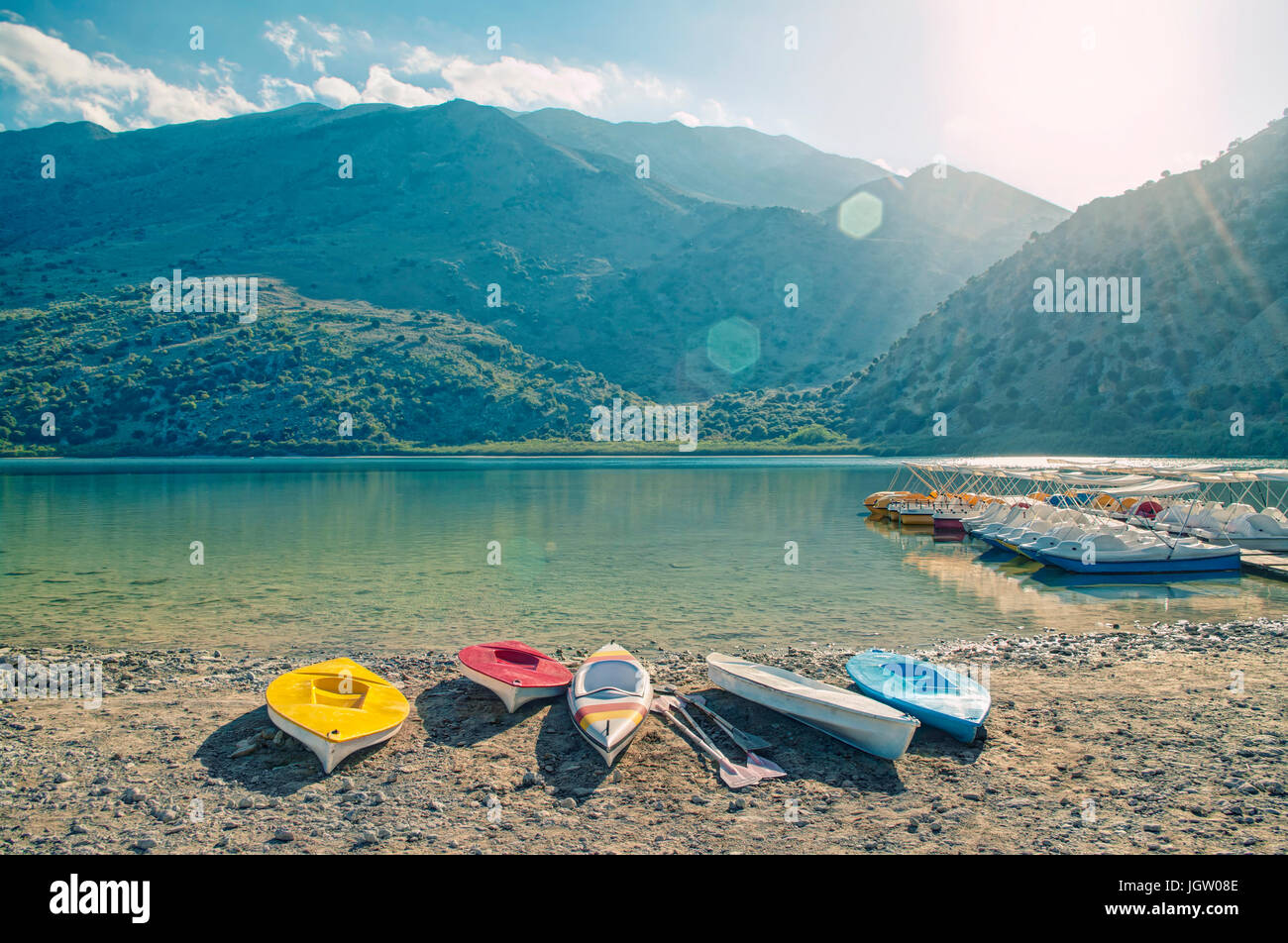 cross-processed image of beautiful lake Kournaskayak surrounded by mountains and paddle boat rental at sunset, Crete, Greece Stock Photo