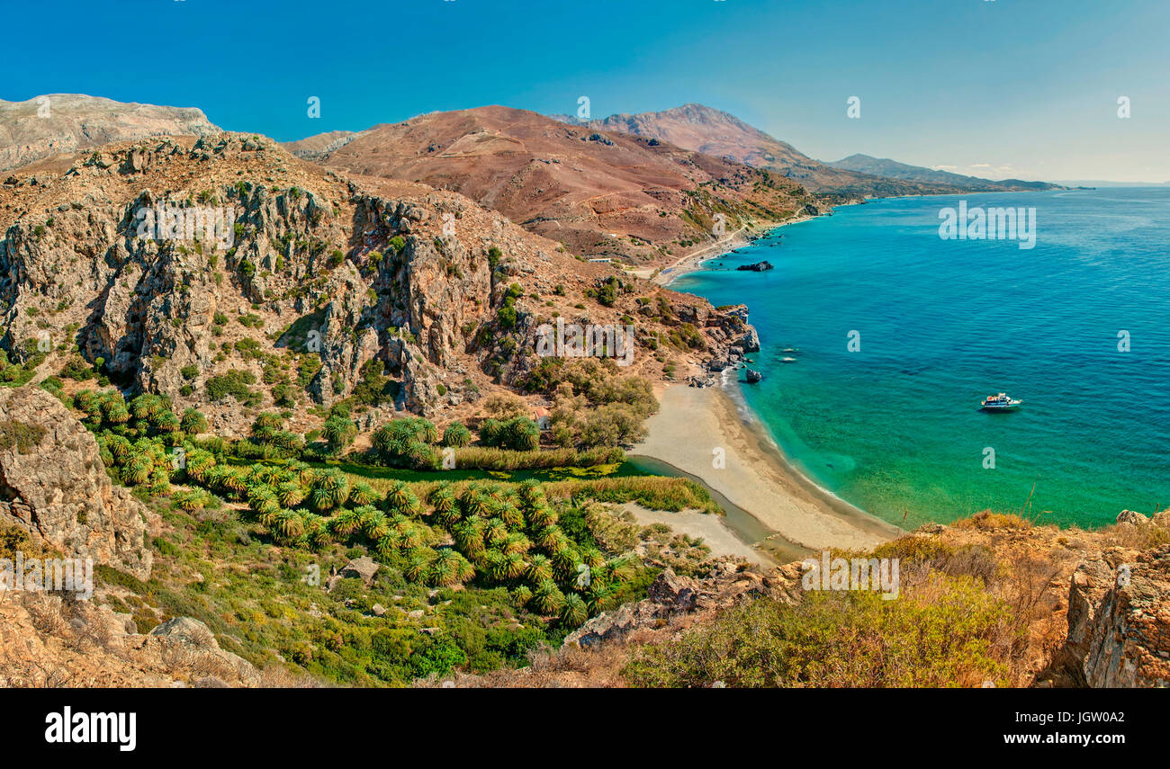 panoramic view of palm tree forest and beach of Preveli surrounded by mountains on sunny summer day, Crete, Greece Stock Photo