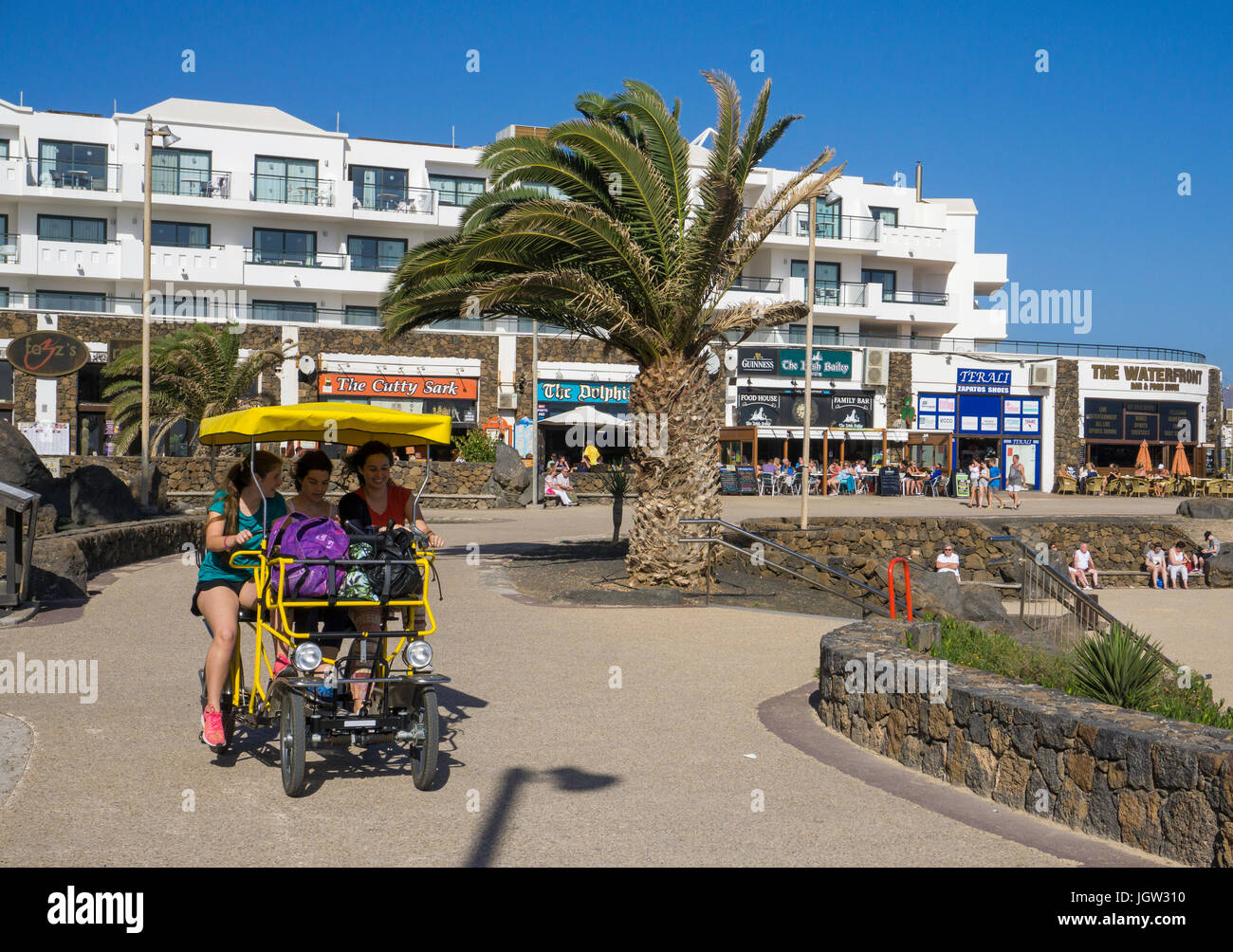 Tourists on 4-wheel bycicle at promenade Playa de las Cucharas, Costa Teguise, Lanzarote island, Canary islands, Spain, Europe Stock Photo
