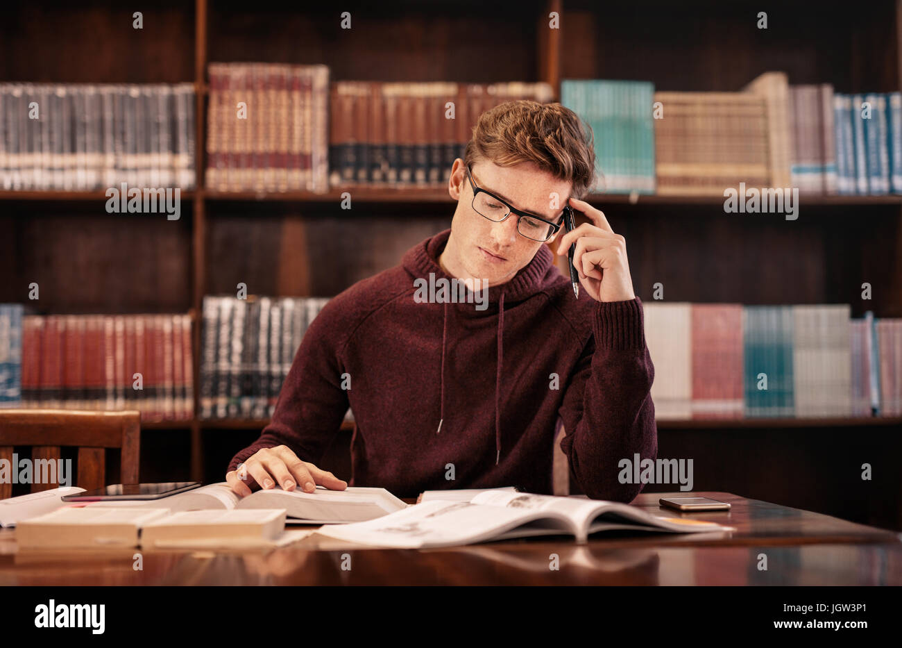 University student reading book in library. Young student preparing for