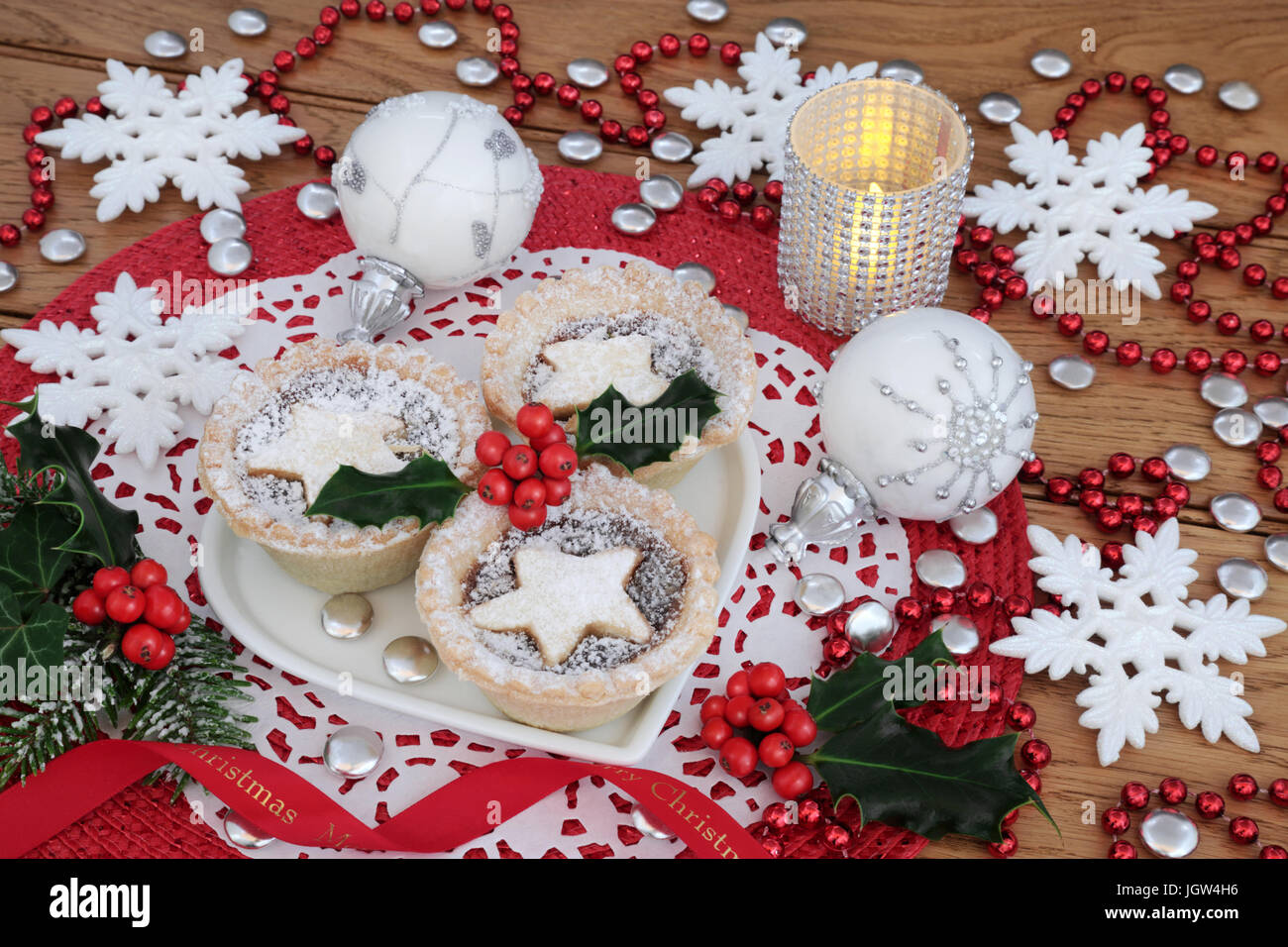 Mince pies with holly on a heart shaped plate with snowflake bauble ...