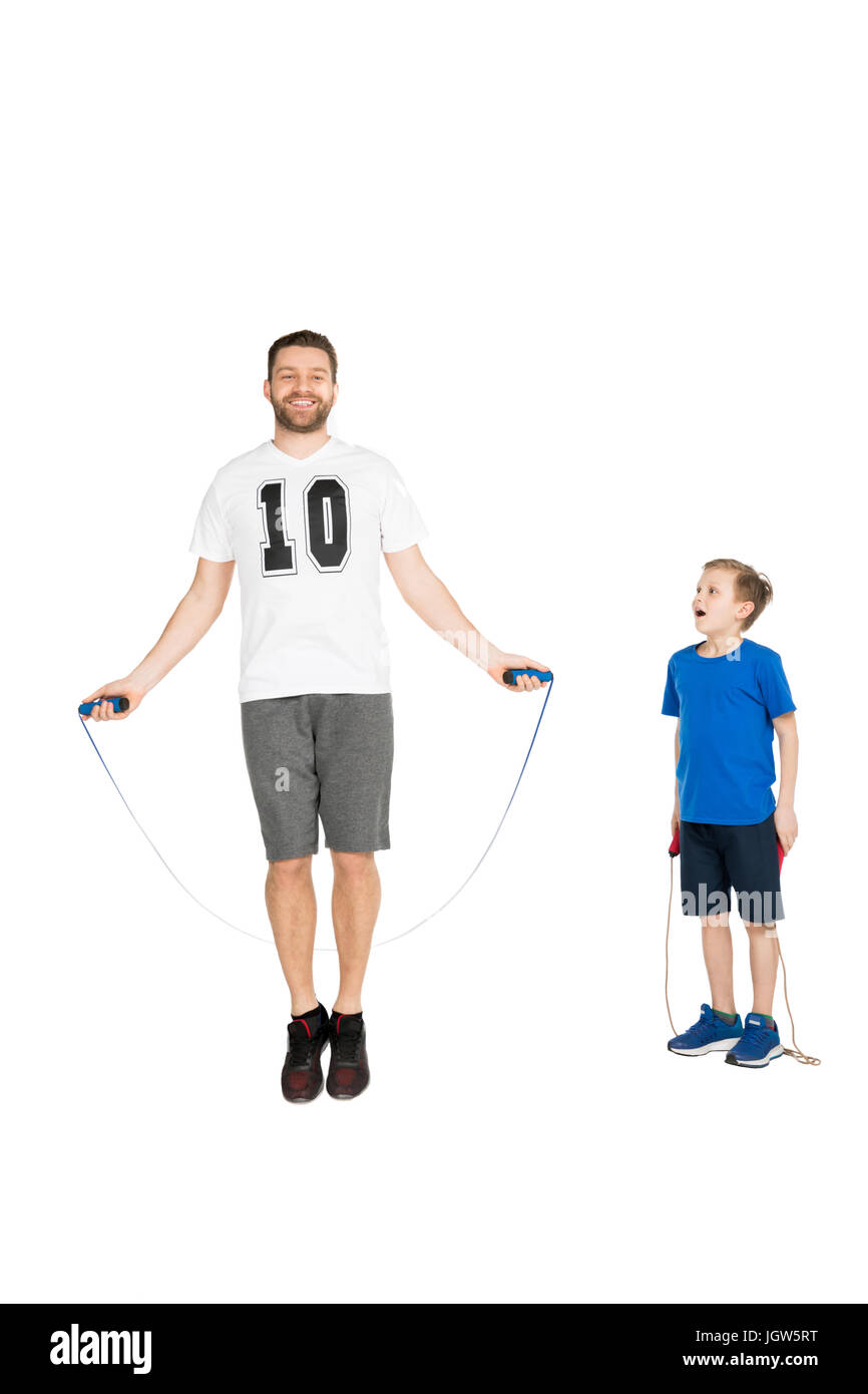 active man jumping with skipping rope with son standing near by isolated on white Stock Photo