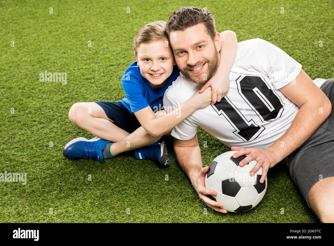 happy son hugging smiling father while lying on grass Stock Photo - Alamy