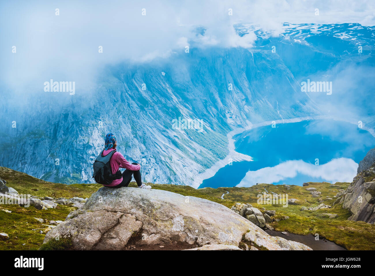 Young woman with backpack standing on fjord coast Stock Photo