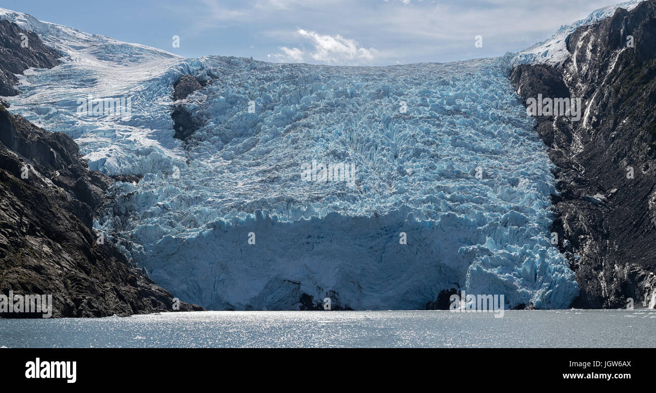 The blue mass of ice that makes up Blackstone Glacier pushes into the sea on a sunny day Stock Photo