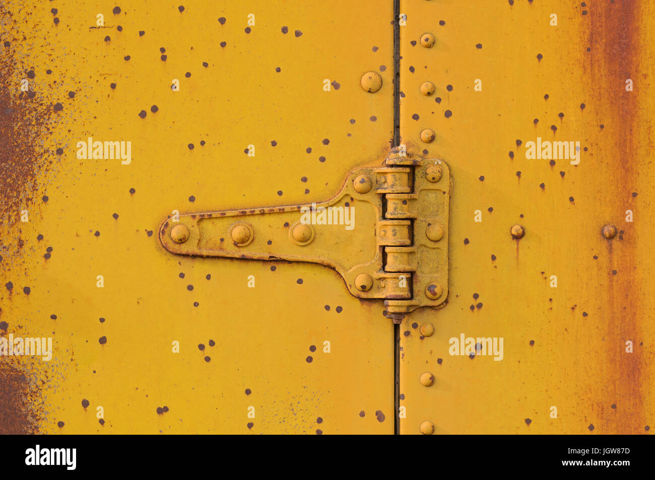 old rusty metal door hinge painted yellow Stock Photo