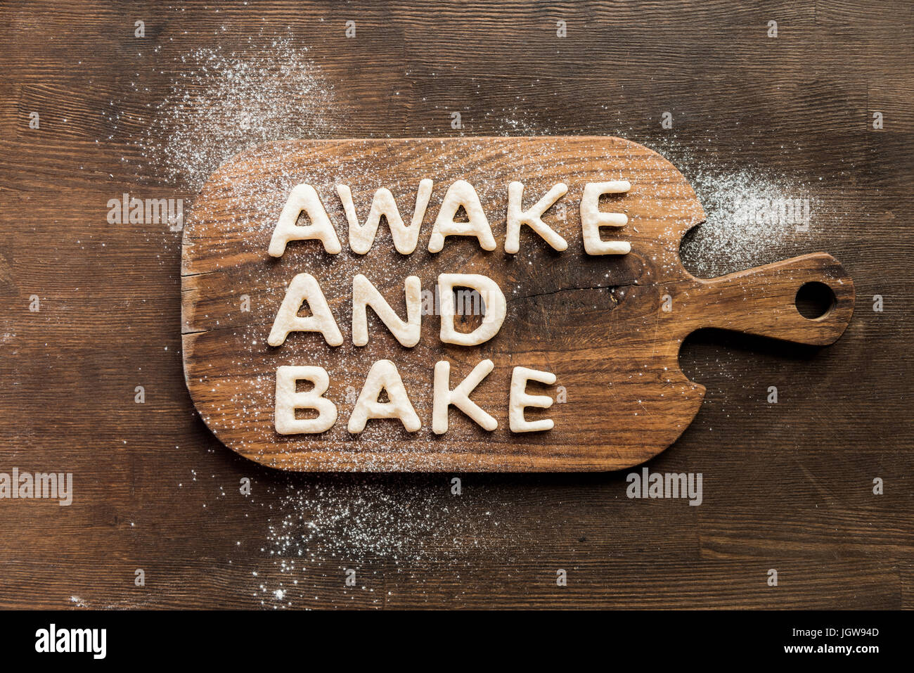 Top view of edible lettering awake and bake made from dough on wooden cutting board, baking cookies concept Stock Photo