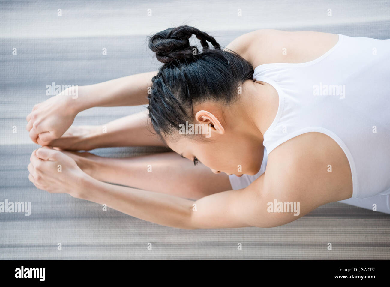 young woman practicing Yoga in forward bending pose Stock Photo